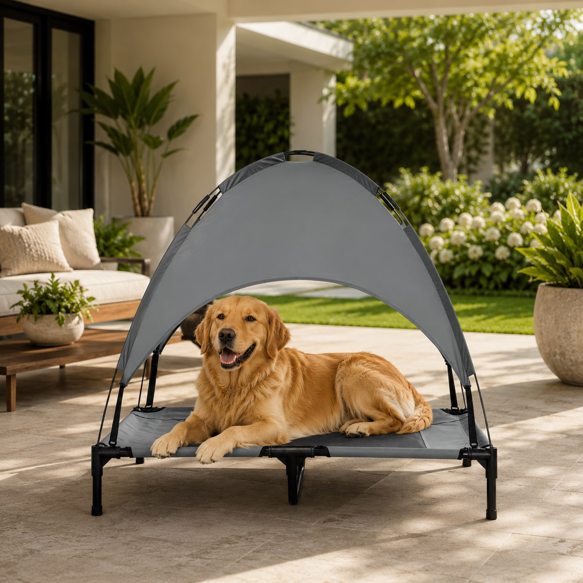 A golden retriever dog lies under a gray pop-up canopy pet bed on a patio in a sunny, modern outdoor living room setting.